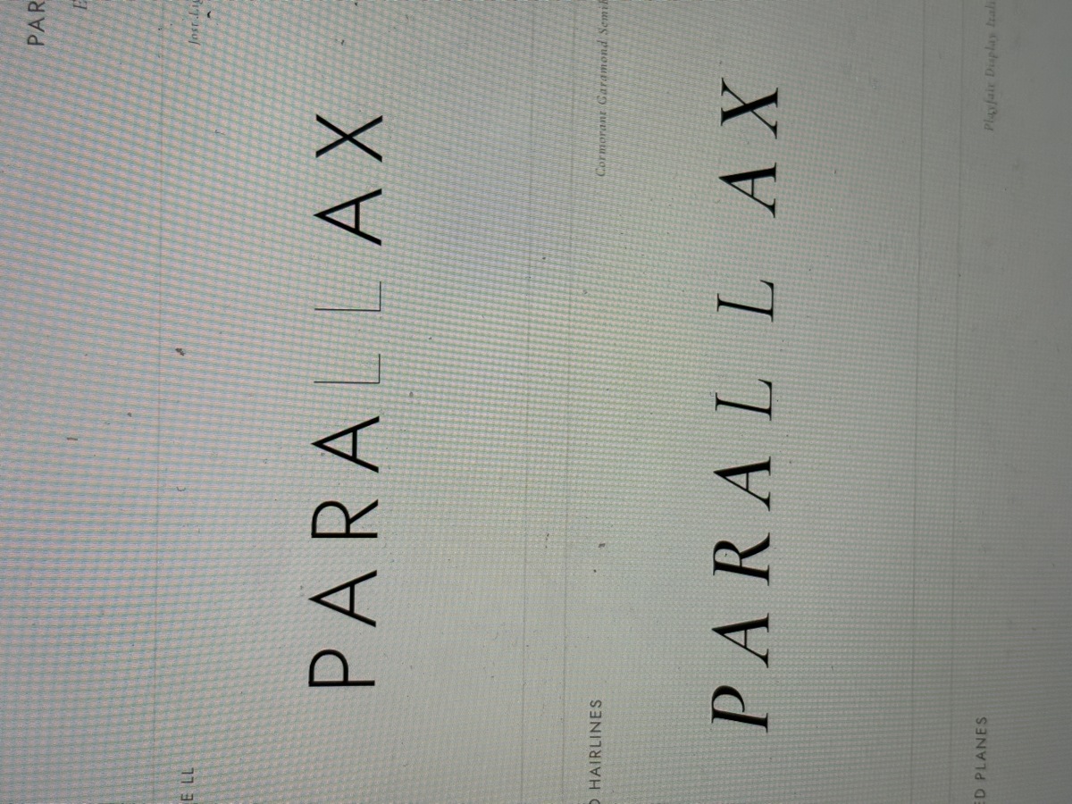 Close-up phone photo of PARALLAX wordmark studies — testing letterform spacing